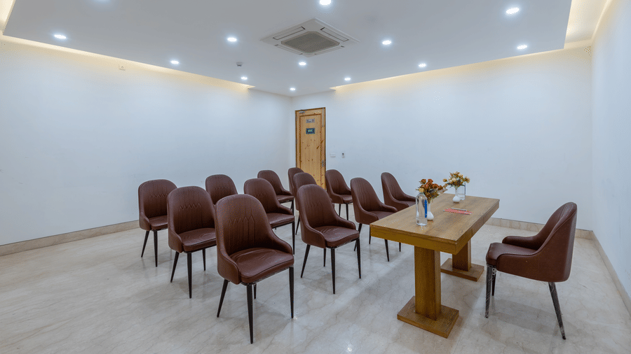  Front view of a conference room with a table placed between a chair and multiple chairs at DLS The Classio